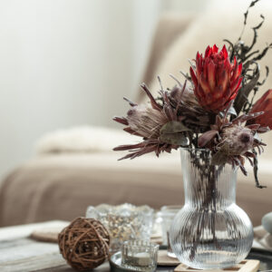 cozy home composition with candles and protea bouquet.